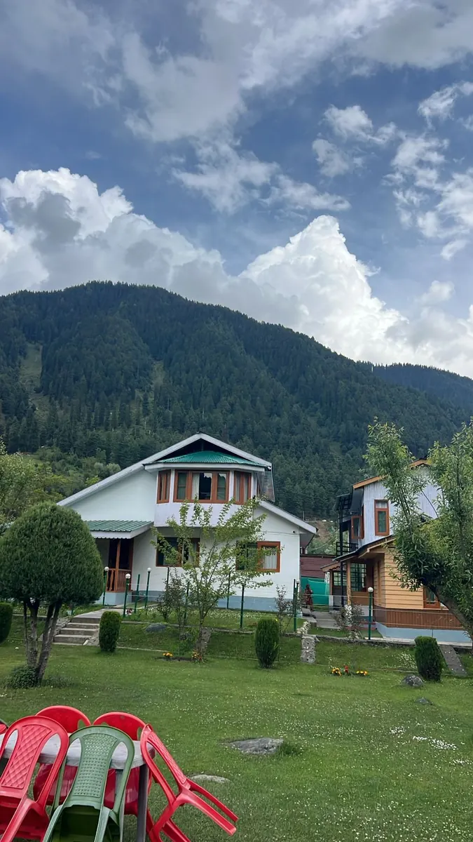 Tulip Cottage Pahalgam exterior with pine-covered mountains behind